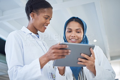 Buy stock photo Shot of two young scientists using a digital tablet in a laboratory