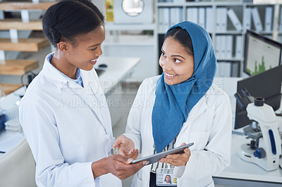 Buy stock photo Shot of two young scientists using a digital tablet in a laboratory