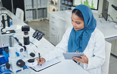 Buy stock photo Shot of a young scientist using a digital tablet while conducting research in a laboratory