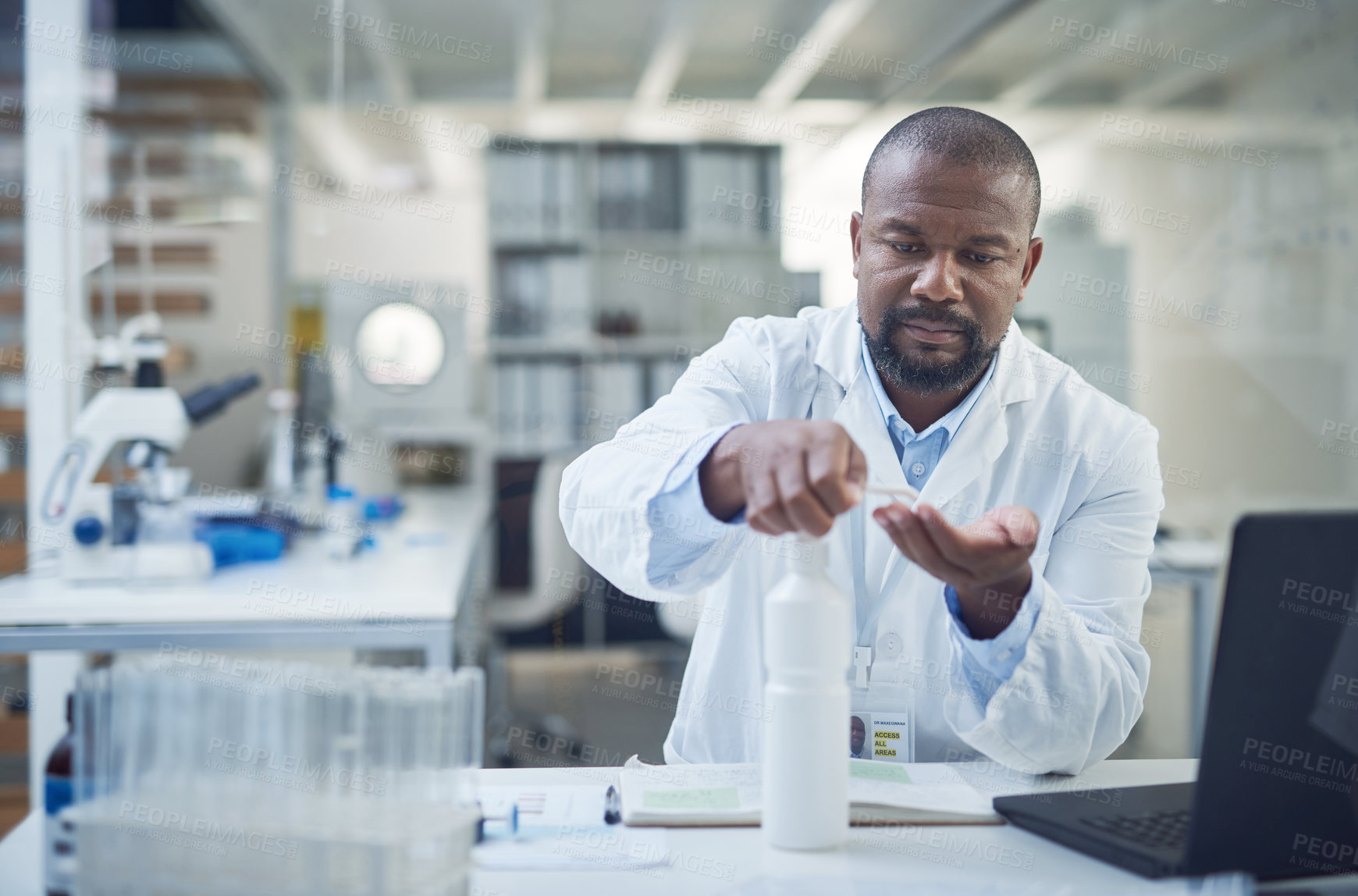 Buy stock photo Shot of a scientist disinfecting his hands while conducting research in a laboratory