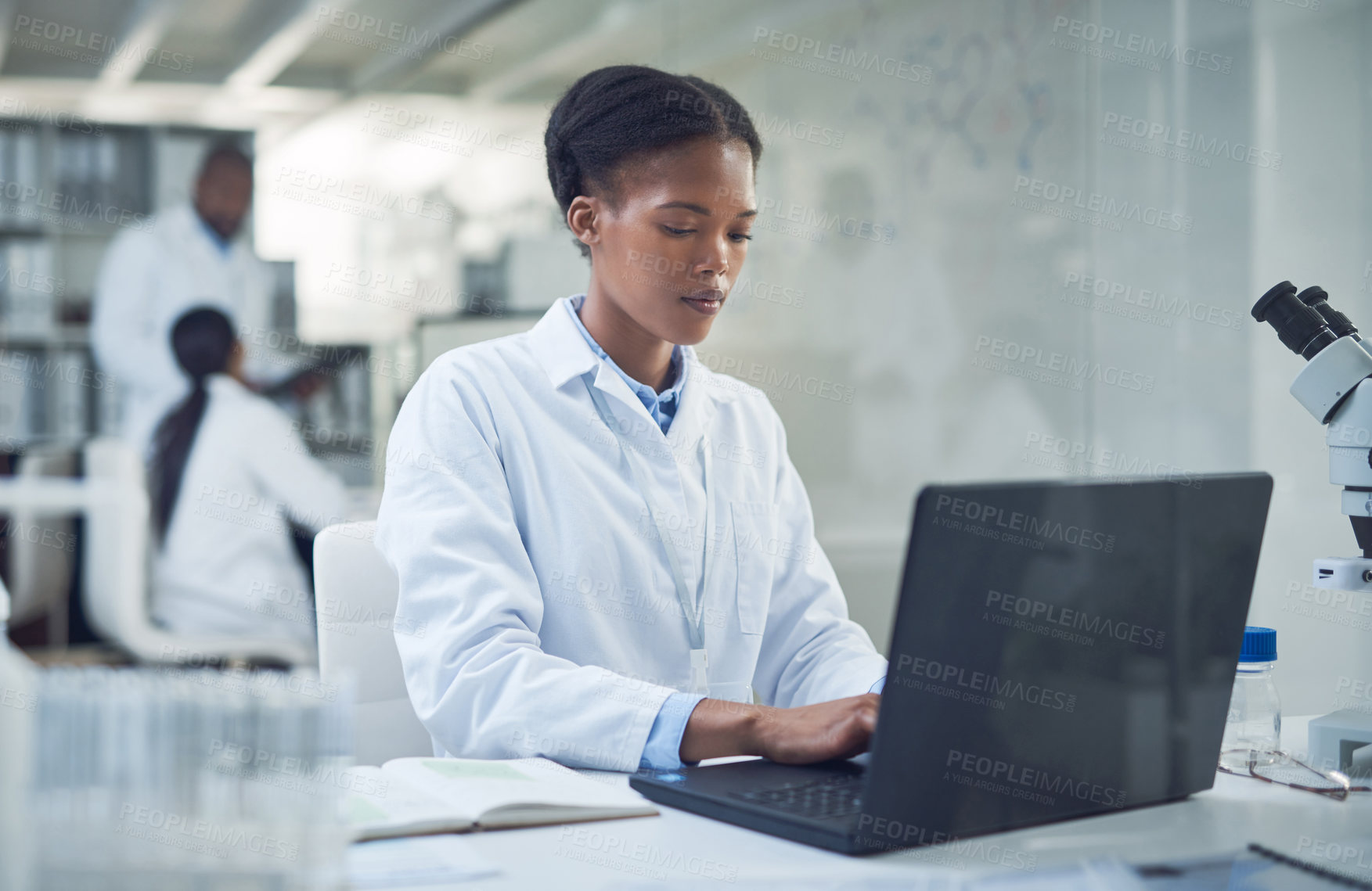 Buy stock photo Shot of a young scientist using a laptop while conducting research in a laboratory