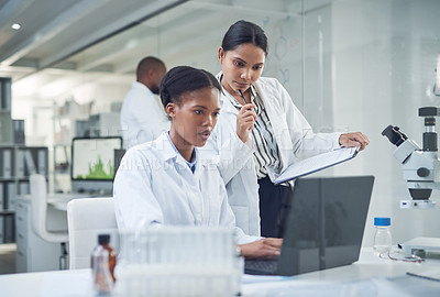 Buy stock photo Shot of two young scientists using a laptop in a laboratory