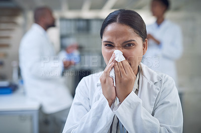 Buy stock photo Shot of a young scientist blowing her nose with a tissue while working in a laboratory