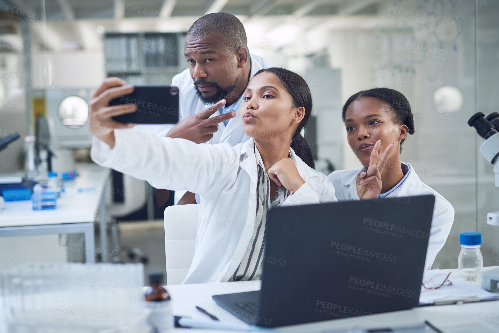 Buy stock photo Shot of a group of young scientists taking a selfie while conducting research in a laboratory