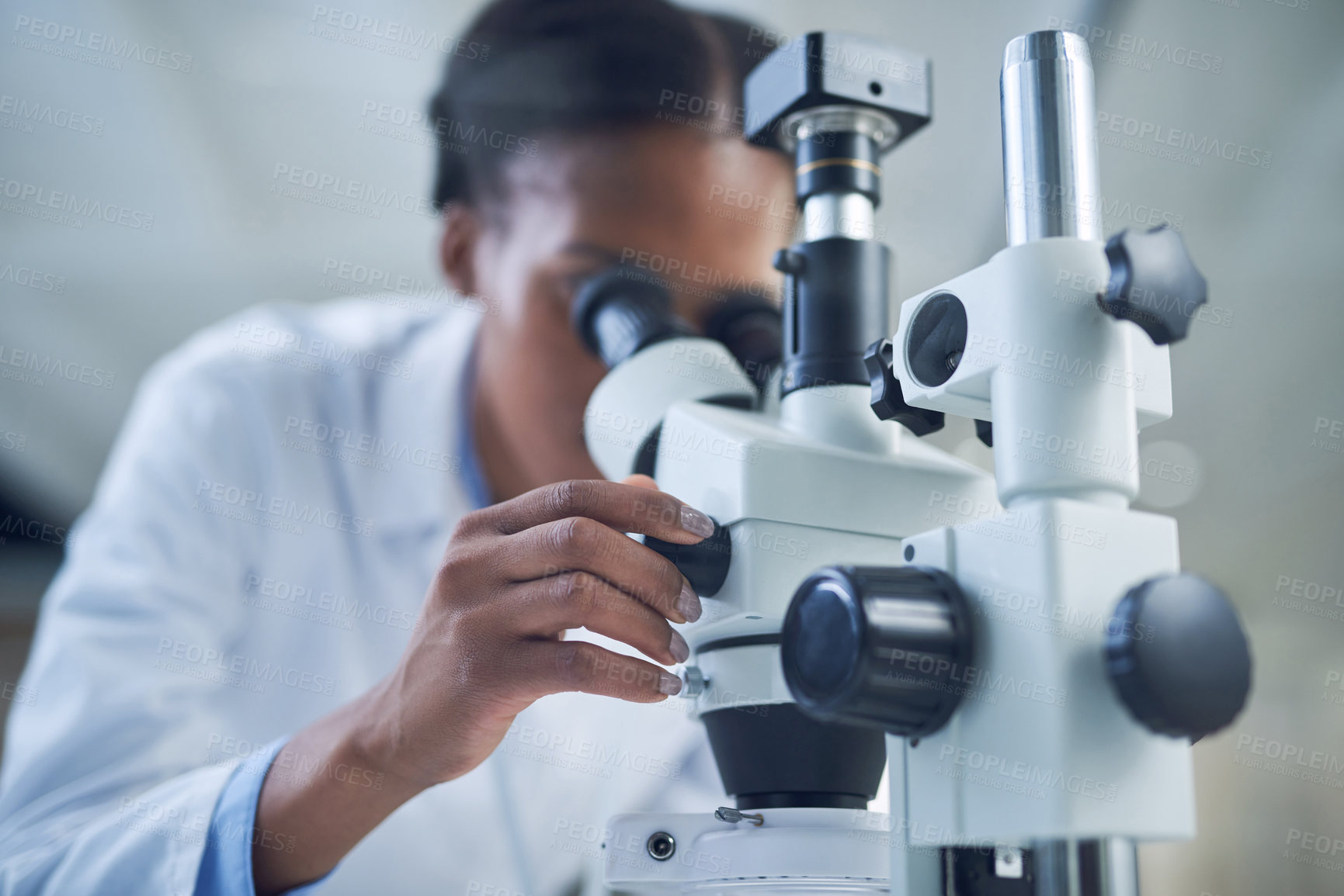 Buy stock photo Shot of a young scientist using a microscope while conducting research in a laboratory
