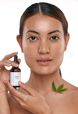 Buy stock photo Shot of a beautiful young woman holding a bottle of CBD oil against a white background