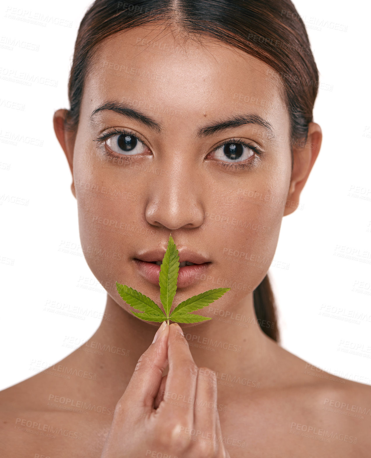 Buy stock photo Shot of a beautiful young woman holding a marijuana leaf against her face