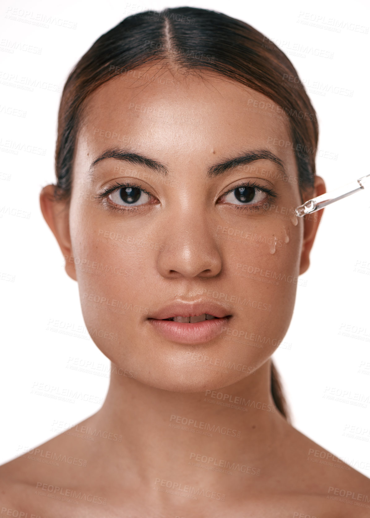 Buy stock photo Shot of a beautiful young woman posing with a serum dropper against her face