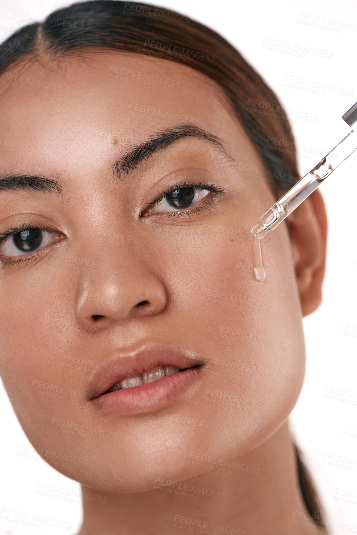 Buy stock photo Shot of a beautiful young woman posing with a serum dropper against her face