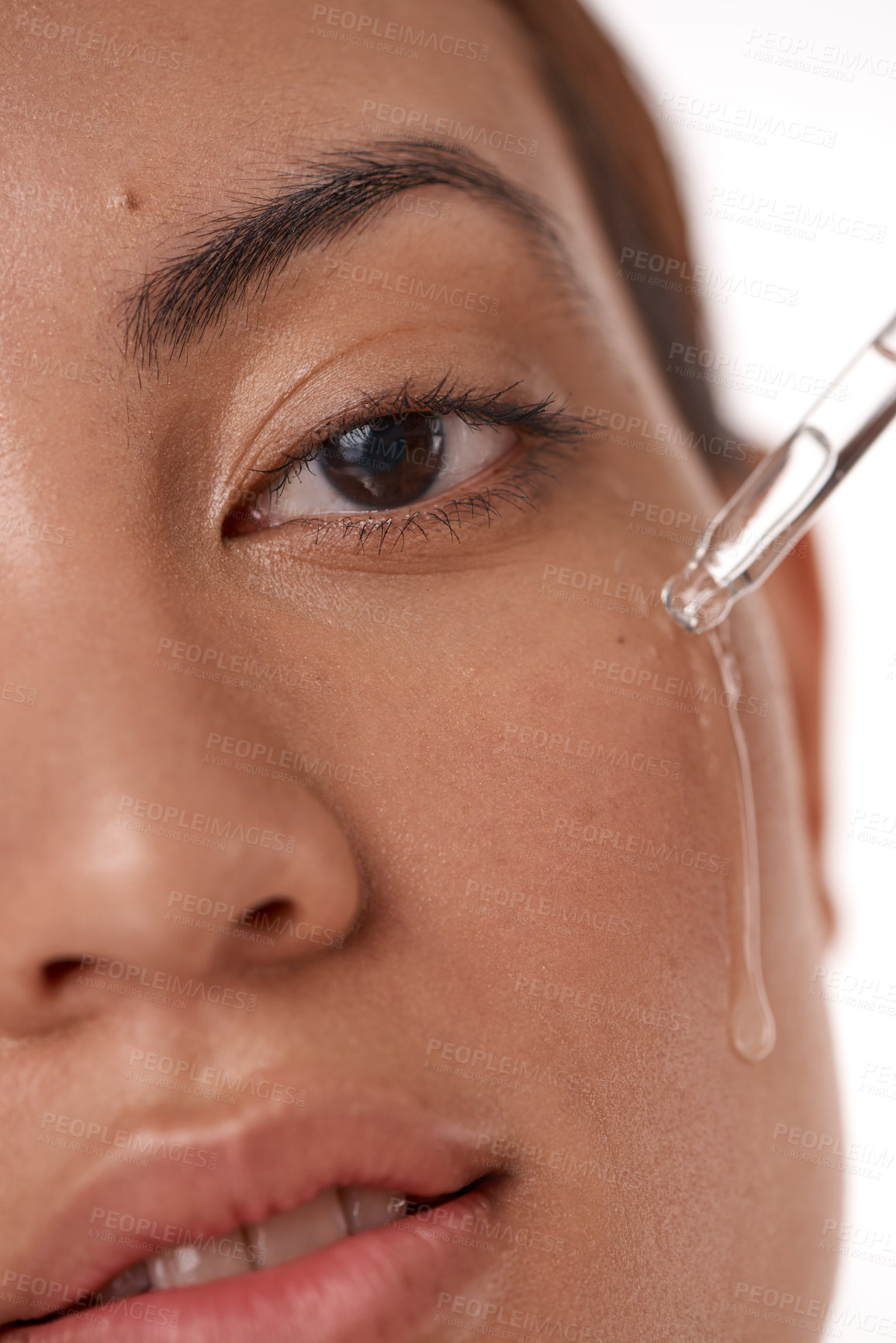 Buy stock photo Shot of a beautiful young woman posing with a serum dropper against her face