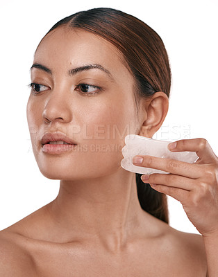Buy stock photo Shot of a beautiful woman using a Gua Sha tool on her face