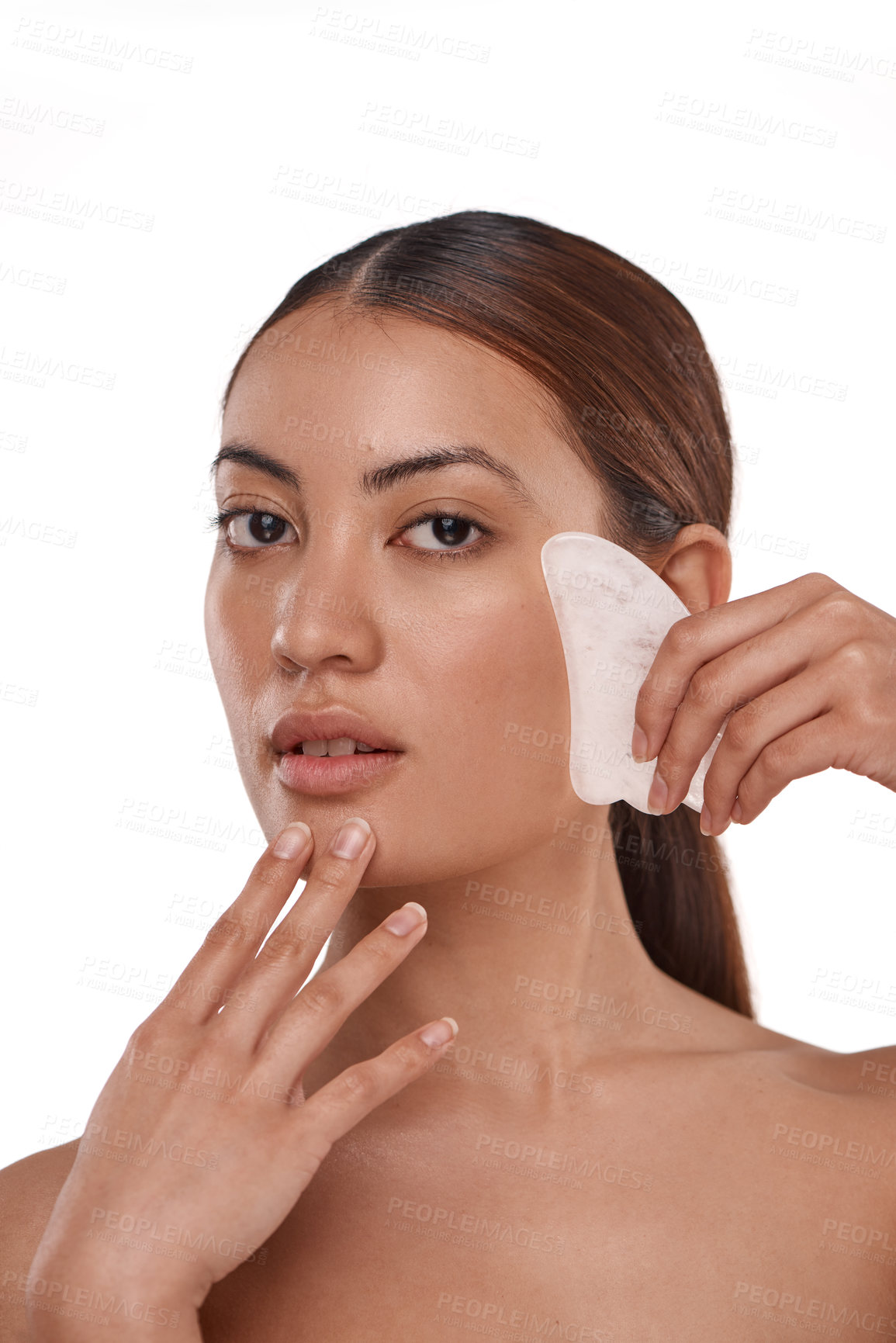 Buy stock photo Shot of a beautiful woman using a Gua Sha tool on her face