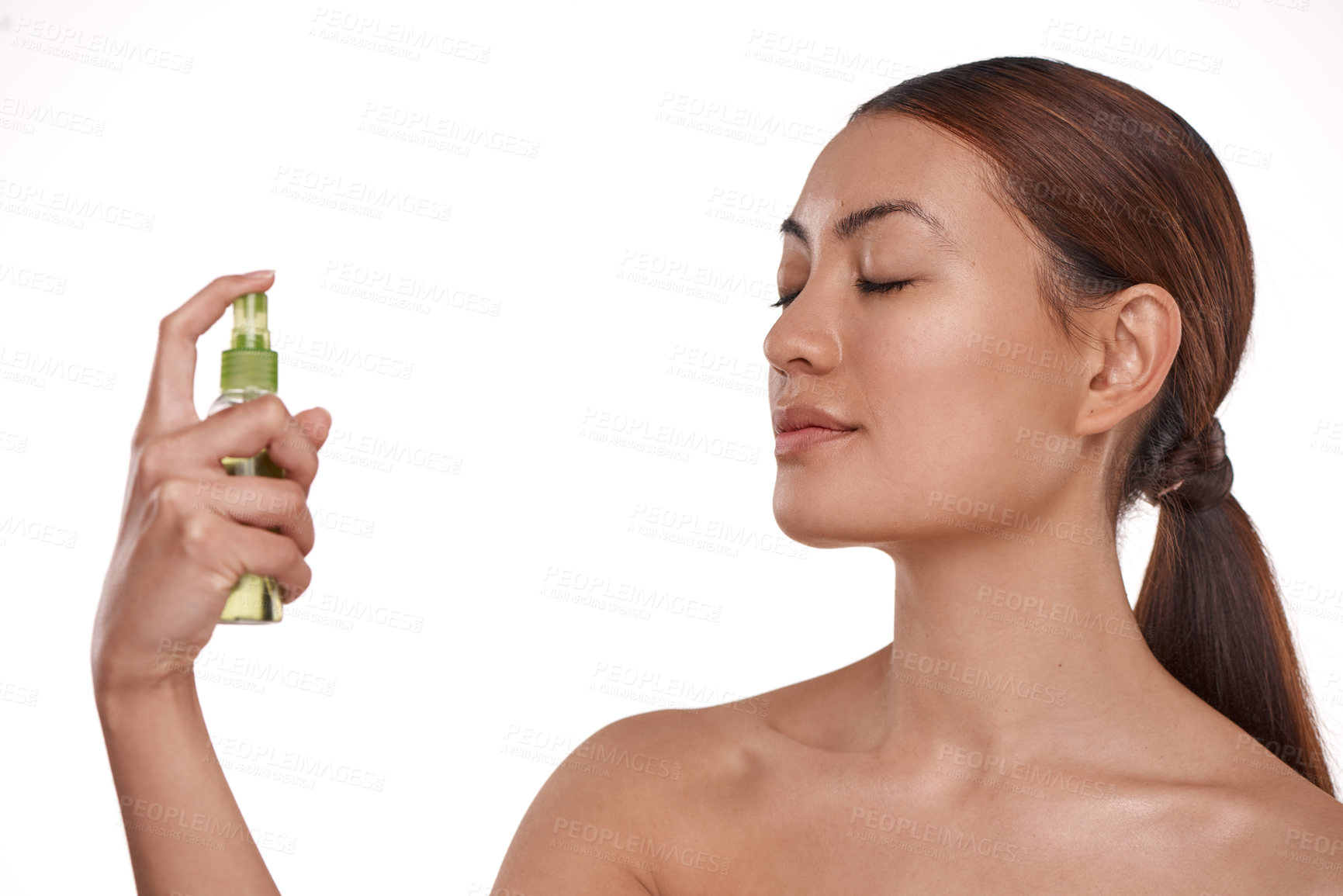 Buy stock photo Shot of a beautiful young woman holding up a bottle of face mist