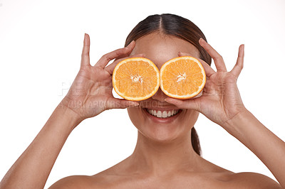 Buy stock photo Shot of a beautiful young woman holding halved oranges over her eyes