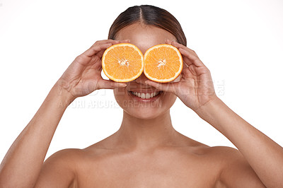 Buy stock photo Shot of a beautiful young woman holding halved oranges over her eyes