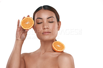 Buy stock photo Shot of a beautiful young woman posing with halved oranges against her skin