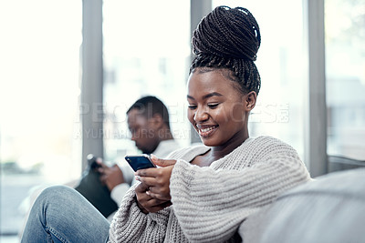 Buy stock photo Shot of a young couple using their smartphones on the sofa at home