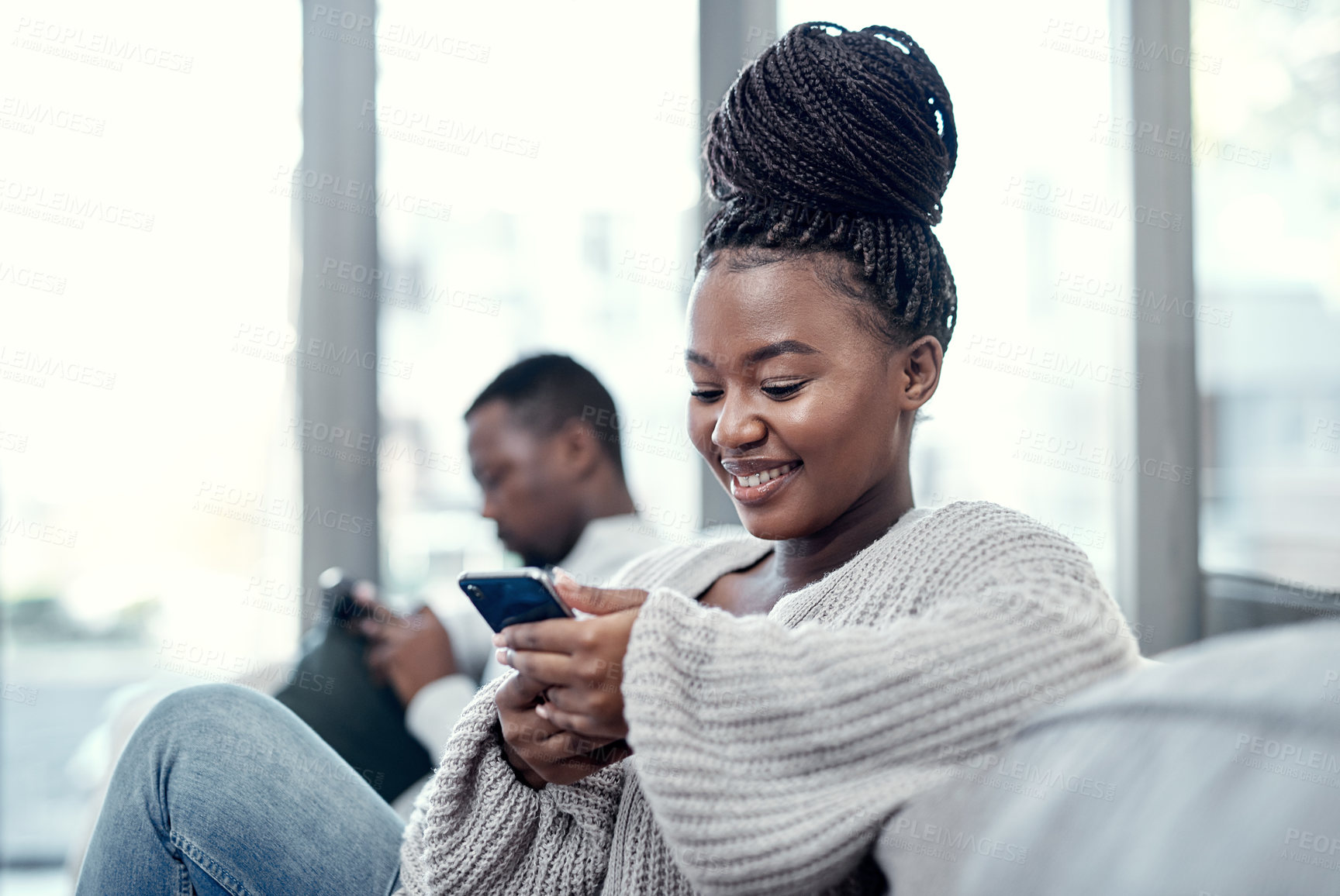 Buy stock photo Shot of a young couple using their smartphones on the sofa at home