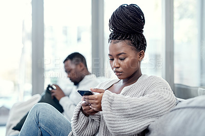 Buy stock photo Angry, serious and annoyed woman giving her boyfriend the silent treatment or cold shoulder after a fight, argument or disagreement as a couple. Female reading a text and ignoring her husband at home