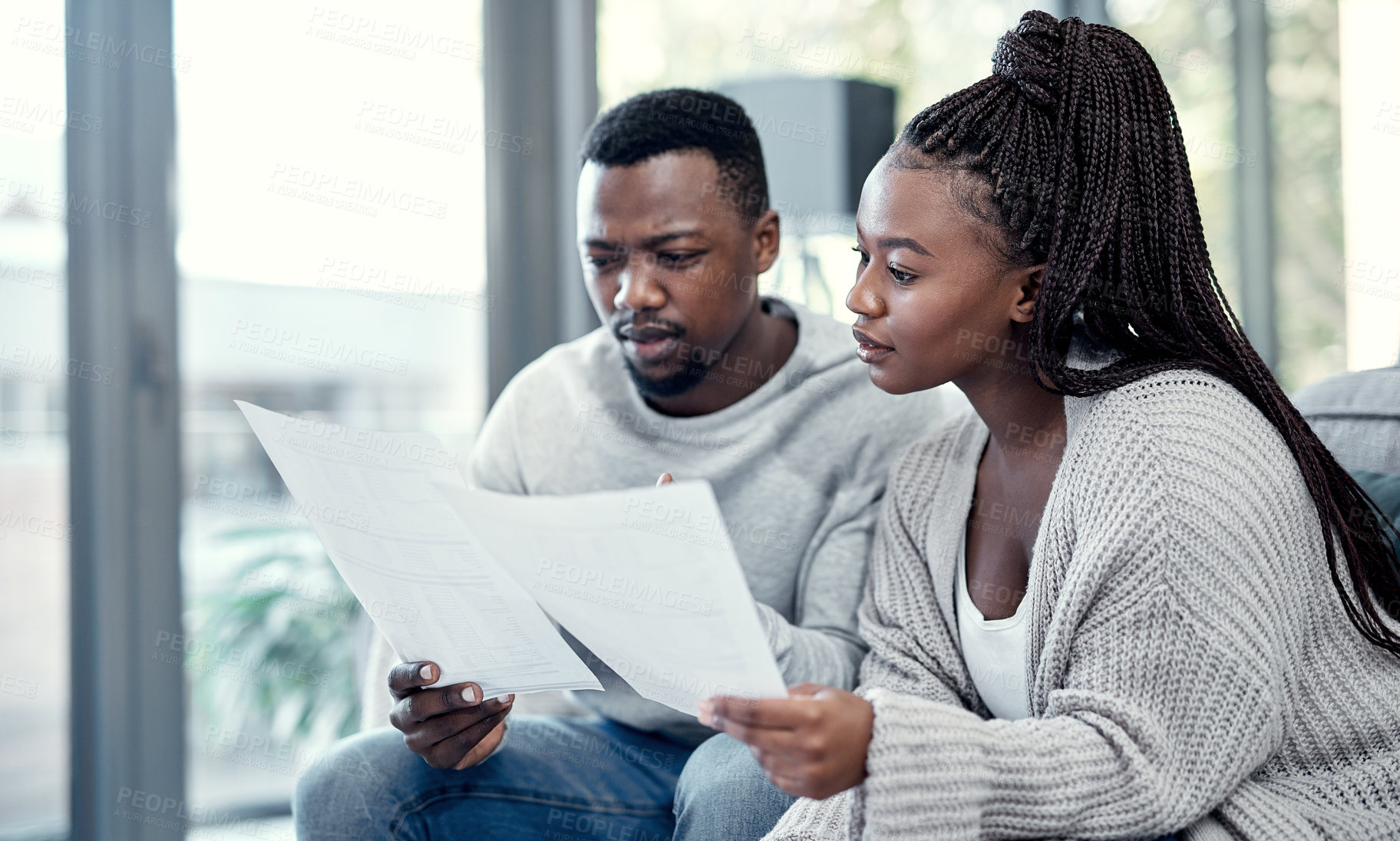 Buy stock photo Shot of a young couple going through paperwork at home