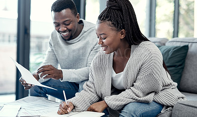Buy stock photo Happy African American couple doing finance planning, writing budget paperwork on sofa at home. Smiling boyfriend and girlfriend discussing insurance bills, savings and investments for future.