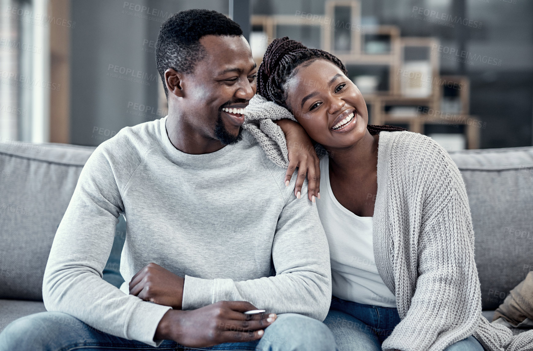 Buy stock photo Happy, in love, and carefree couple relaxing, smiling and laughing together at home portrait while enjoying their weekend spent indoors. Young African wife and loving husband bonding on their couch