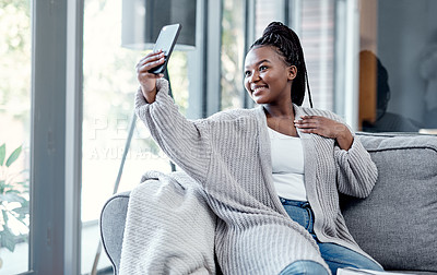 Buy stock photo Shot of a young woman using a smartphone to take selfies while relaxing on the sofa at home