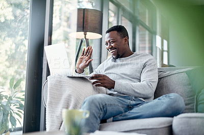 Buy stock photo Shot of a young man using a laptop to make a video call on the sofa at home