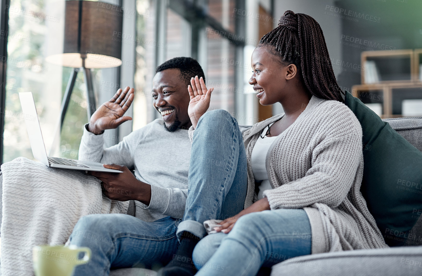 Buy stock photo Happy couple waving while talking on video call and online chat on a laptop webcam in a lounge at home. Smiling man and woman having conversation while connecting with virtual contact on the internet