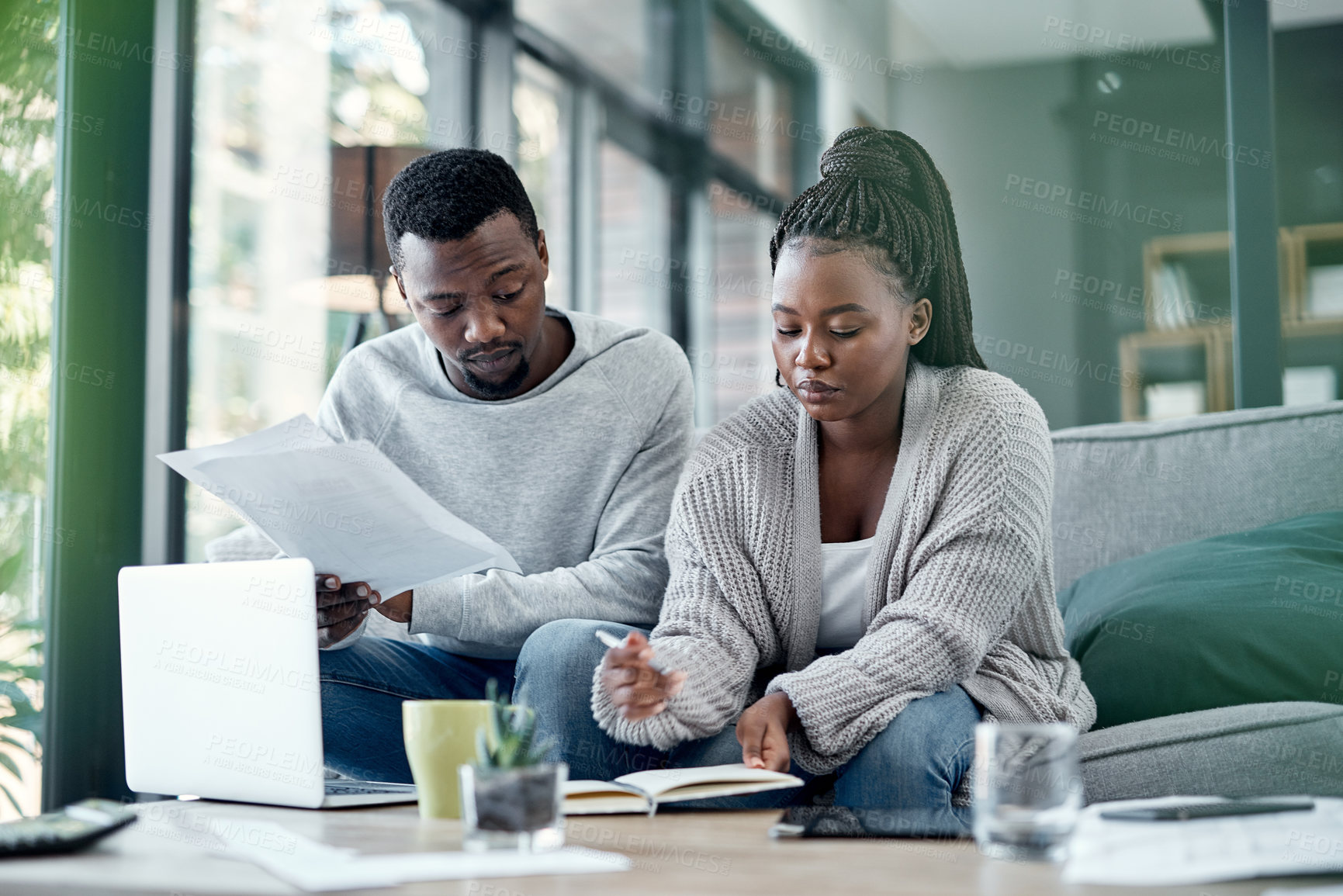 Buy stock photo Shot of a young couple going through paperwork at home