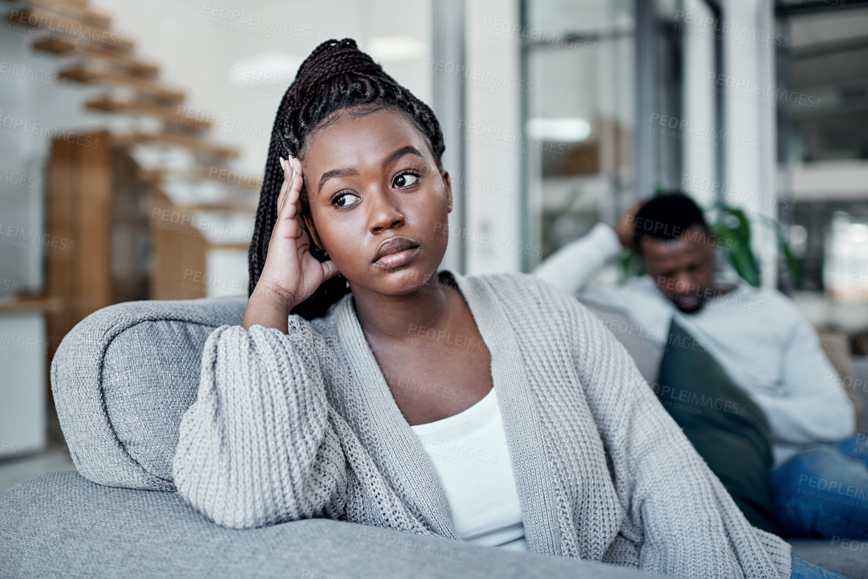 Buy stock photo Shot of a young couple ignoring each other after having an argument on the sofa at home