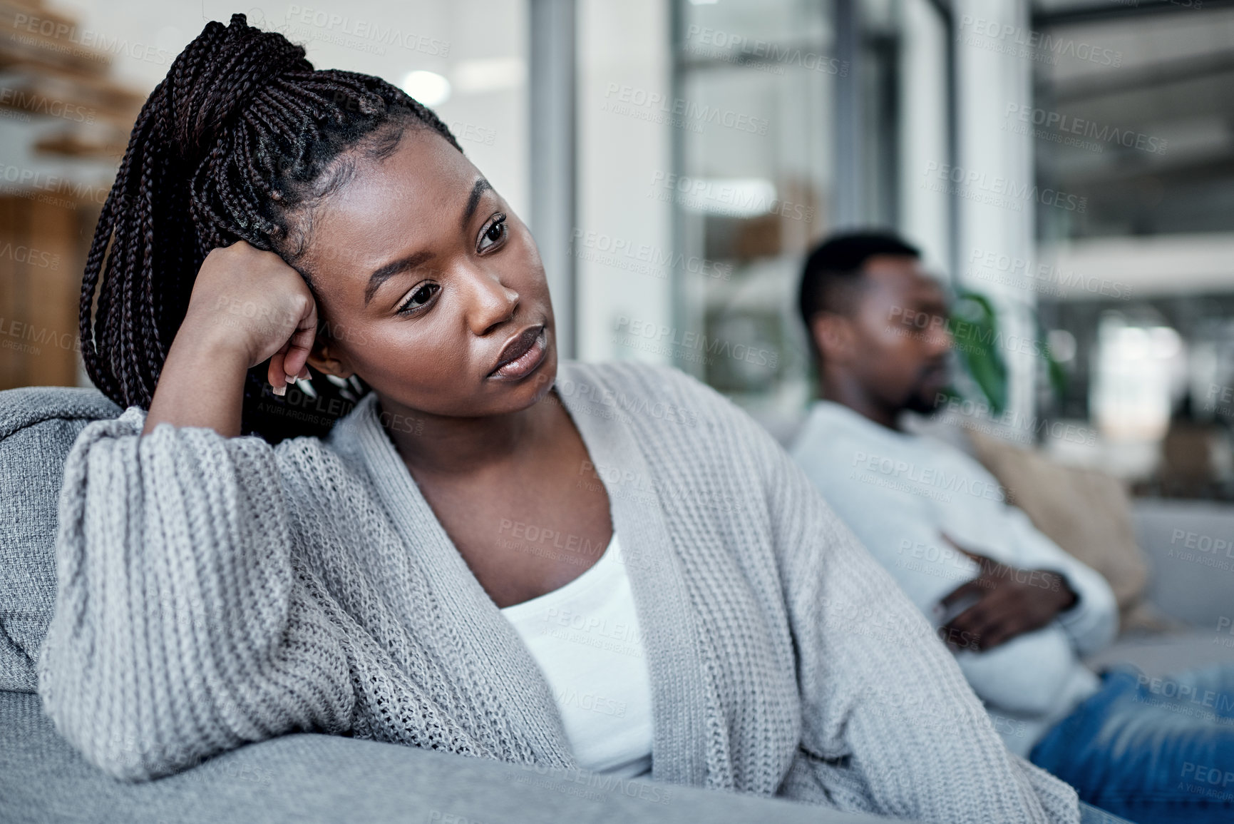 Buy stock photo Shot of a young couple ignoring each other after having an argument on the sofa at home