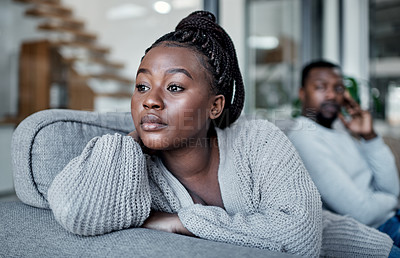 Buy stock photo Shot of a young couple ignoring each other after having an argument on the sofa at home