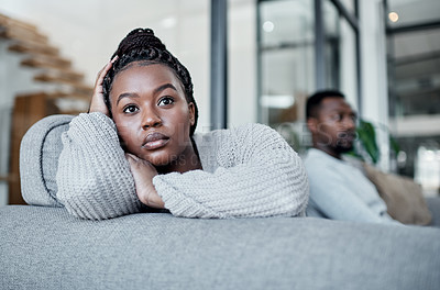 Buy stock photo Shot of a young couple ignoring each other after having an argument on the sofa at home