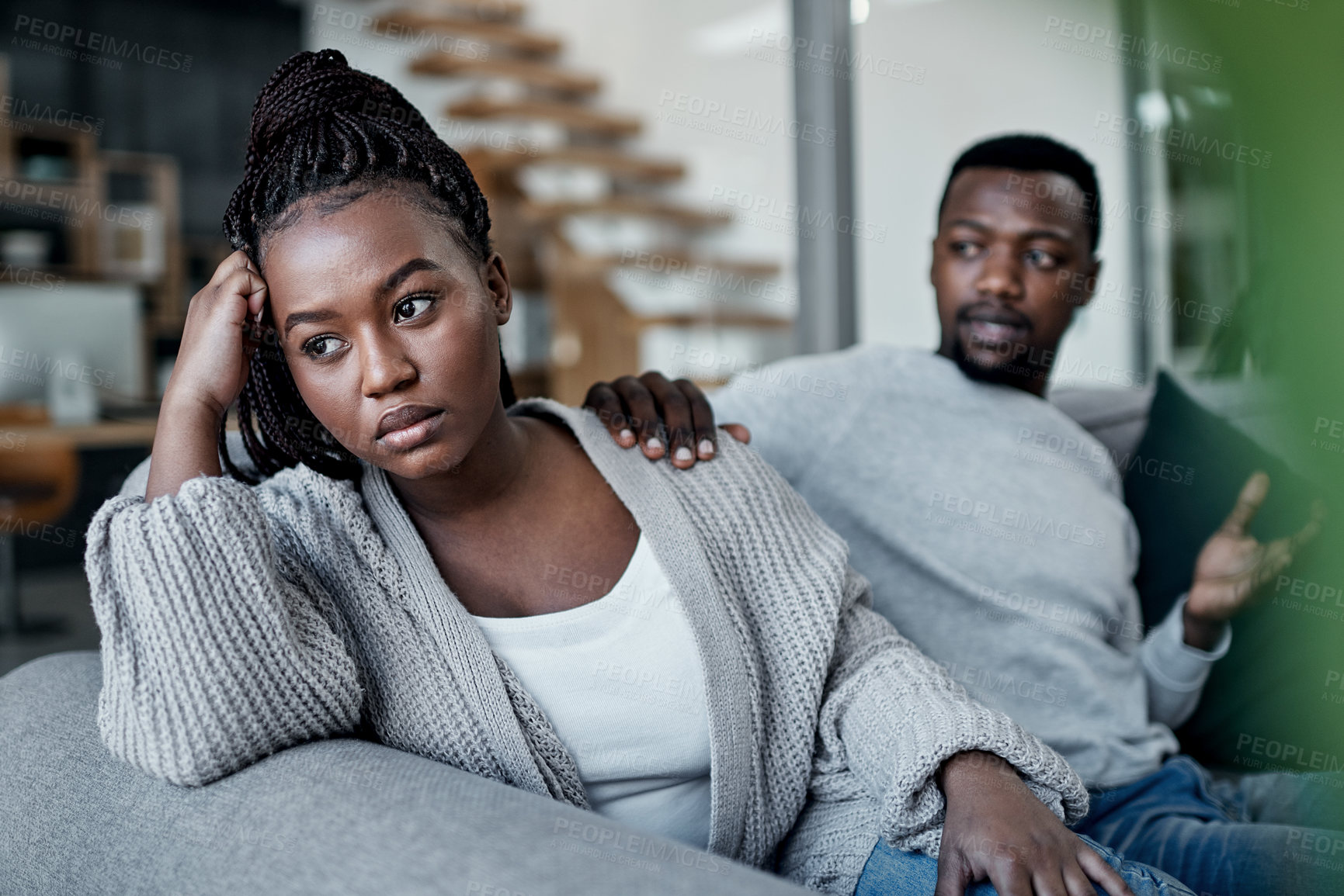 Buy stock photo Shot of a young couple reaching out to his wife after having an argument on the sofa at home