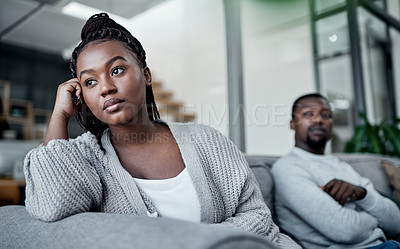 Buy stock photo Shot of a young couple ignoring each other after having an argument on the sofa at home