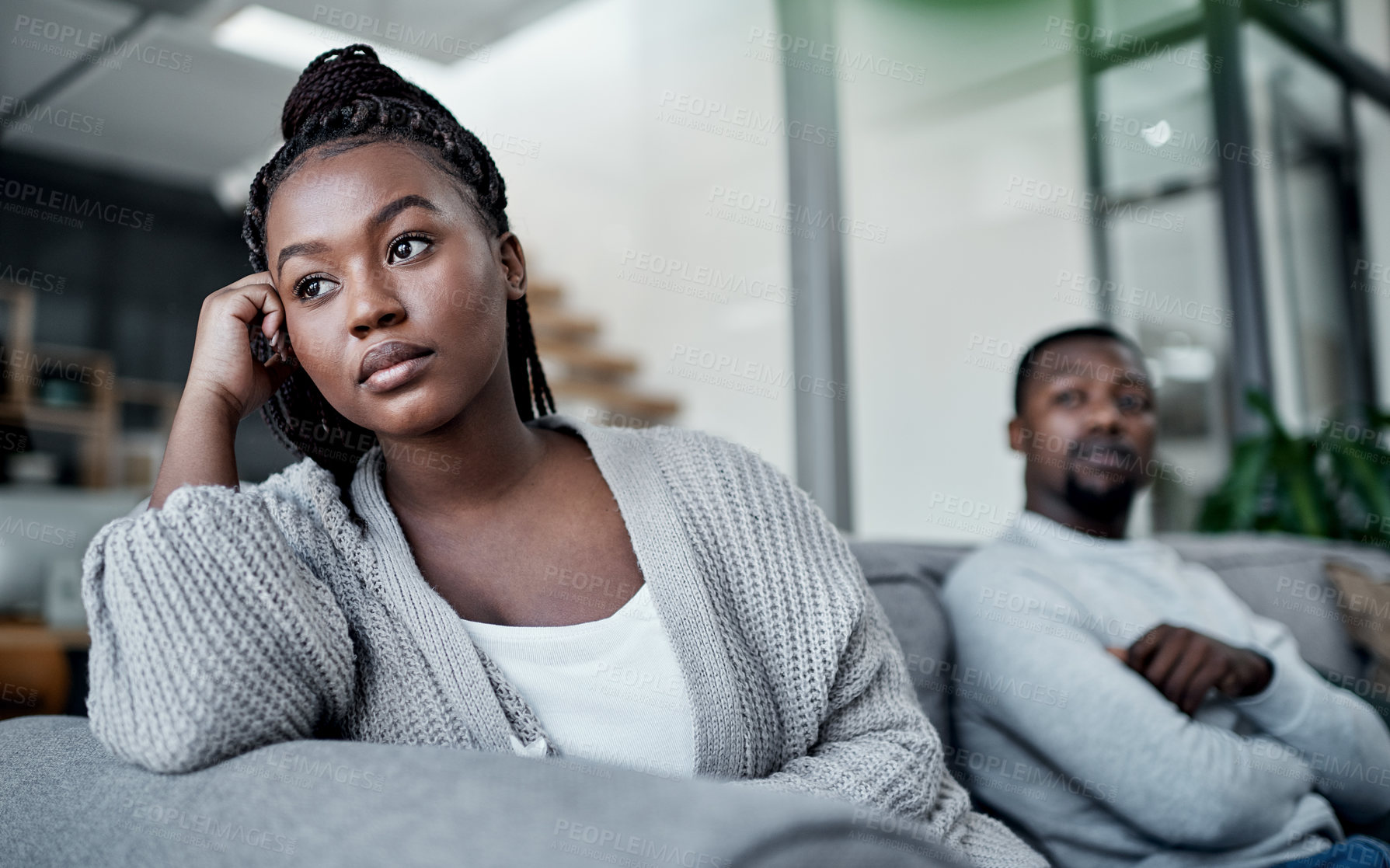 Buy stock photo Shot of a young couple ignoring each other after having an argument on the sofa at home