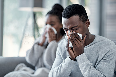 Buy stock photo Shot of a young couple blowing their noses on the sofa at home