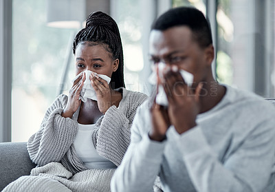 Buy stock photo Shot of a young couple blowing their noses on the sofa at home