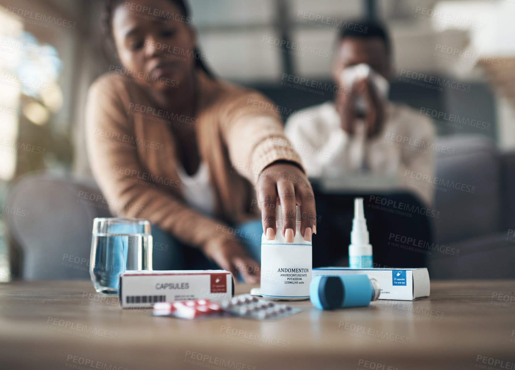 Buy stock photo Cropped shot of a young couple sitting together at home and feeling sick while taking their medication
