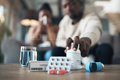 Buy stock photo Cropped shot of an unrecognizable couple sitting together at home and feeling sick while taking their medication