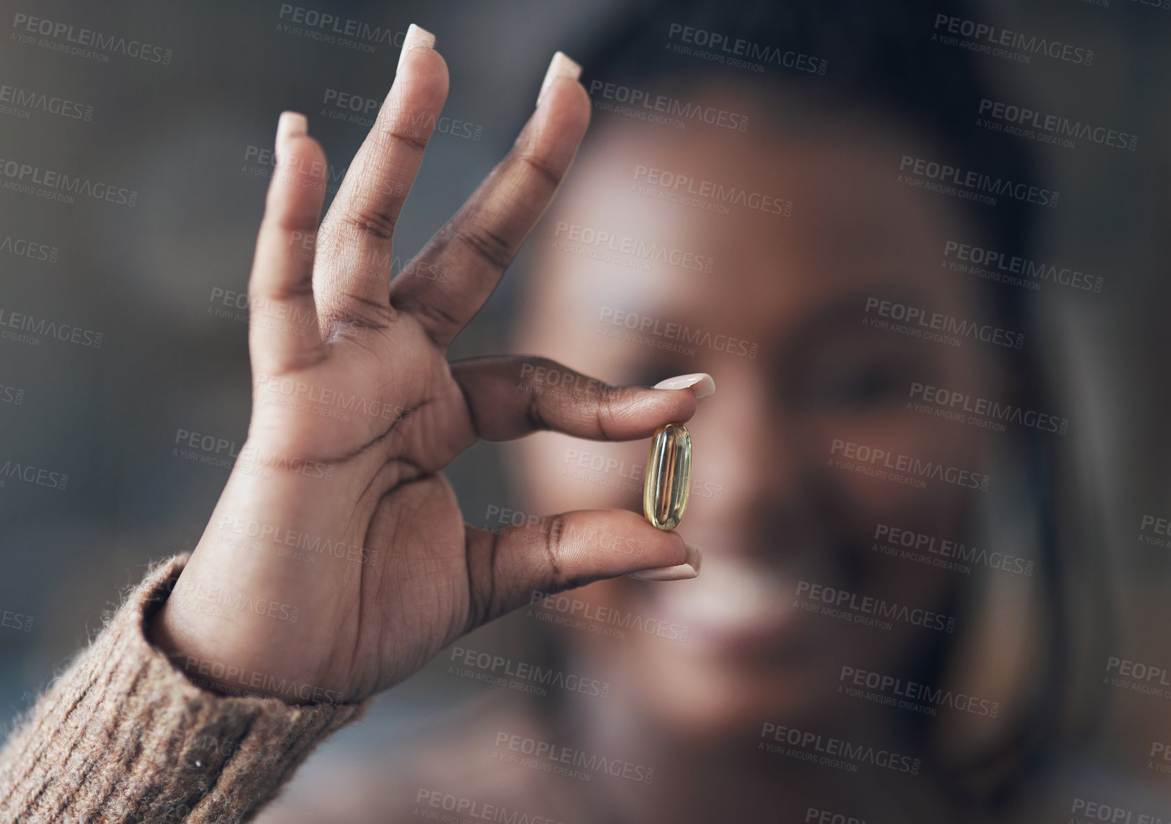 Buy stock photo Cropped shot of an unrecognizable woman holding a pill while sitting alone in her living room