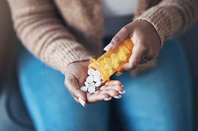 Buy stock photo Cropped shot of an unrecognizable woman sitting alone and taking pills out of a pill bottle in her living room