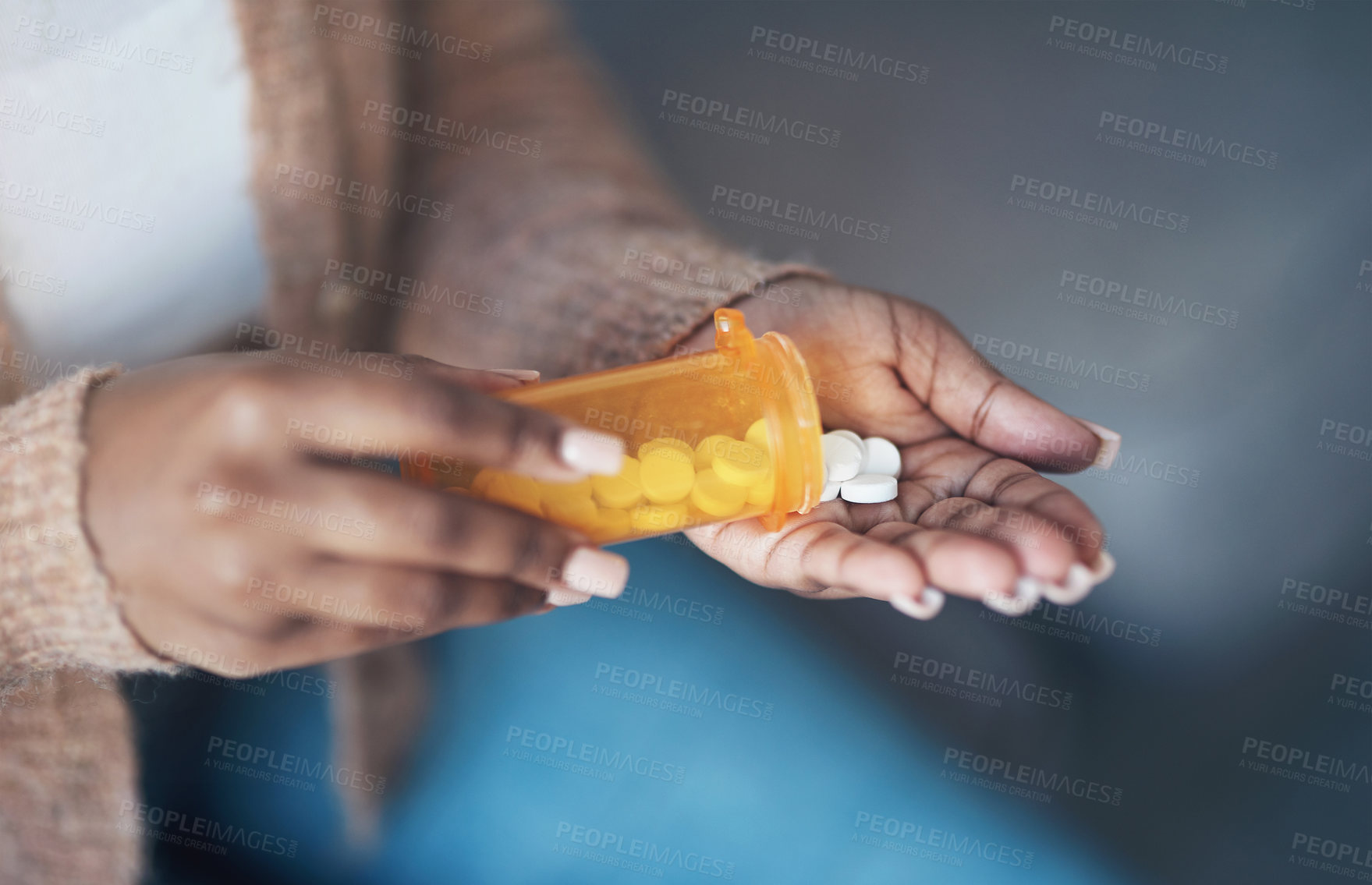 Buy stock photo Cropped shot of an unrecognizable woman sitting alone and taking pills out of a pill bottle in her living room