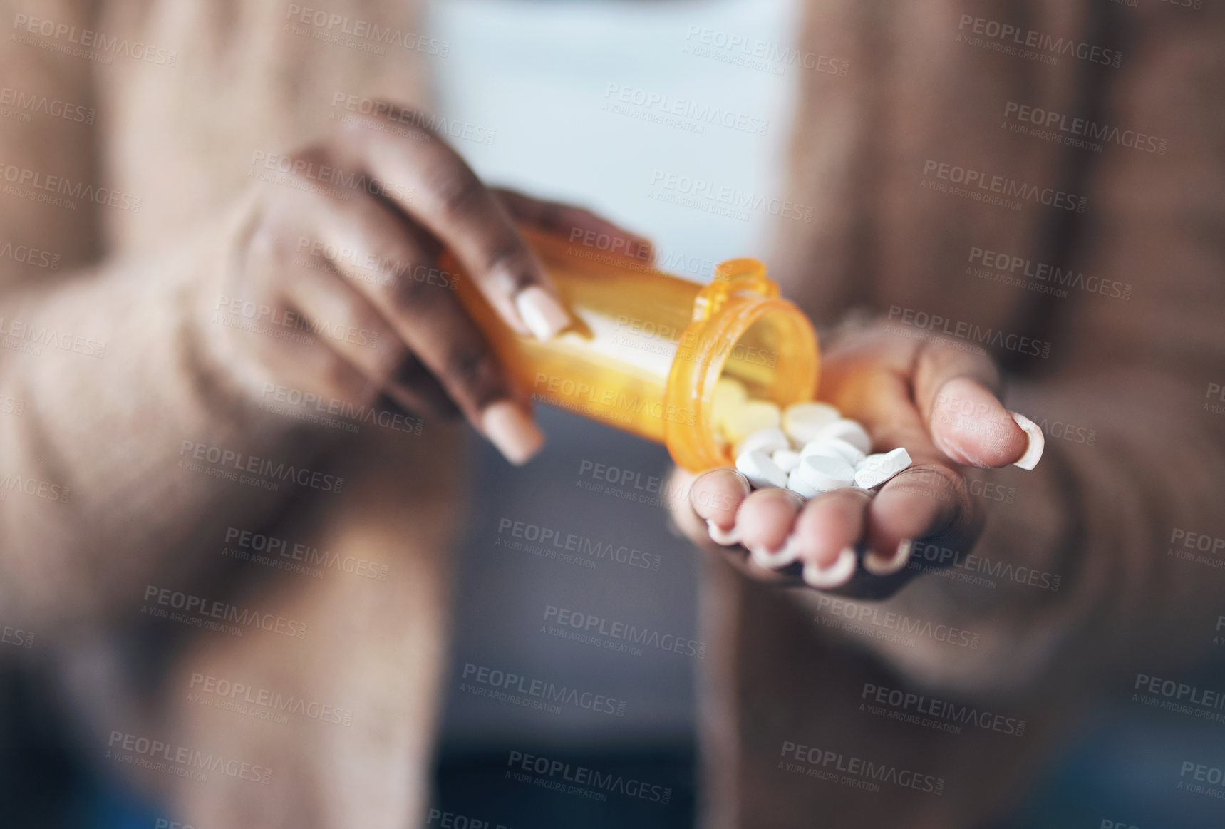 Buy stock photo Cropped shot of an unrecognizable woman sitting alone and taking pills out of a pill bottle in her living room