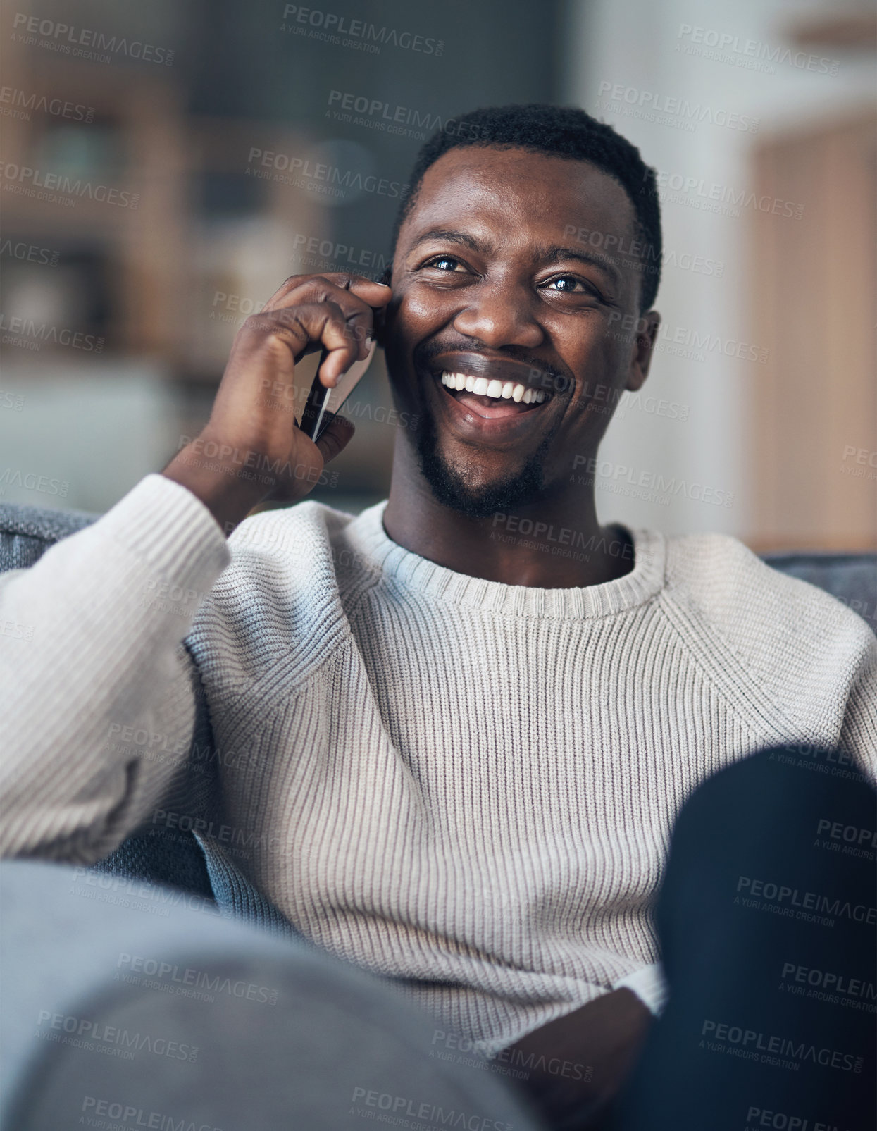 Buy stock photo Cropped shot of a handsome young man sitting alone in his living room and using his cellphone