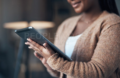 Buy stock photo Cropped shot of an unrecognizable woman sitting alone in her living room and using her tablet