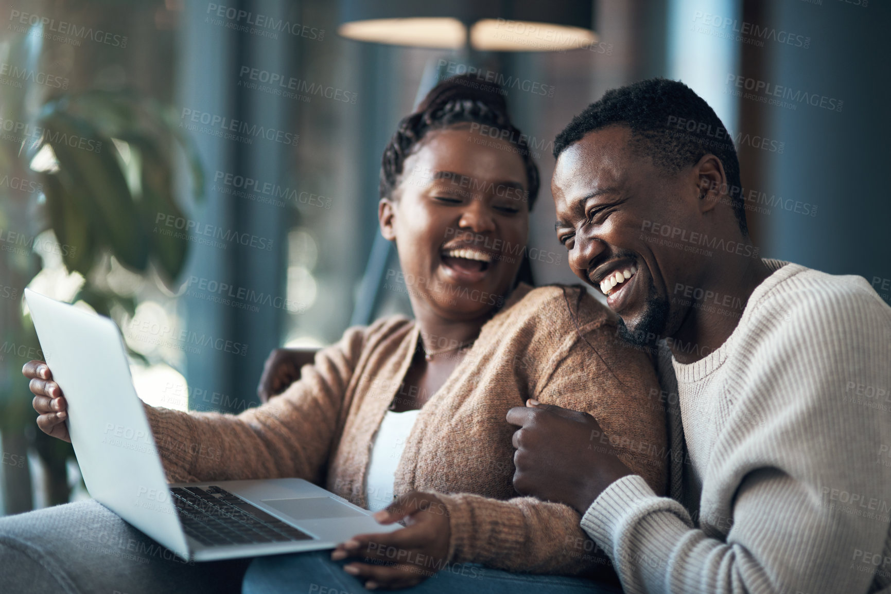 Buy stock photo Cropped shot of a happy young couple sitting together and using a laptop in their living room