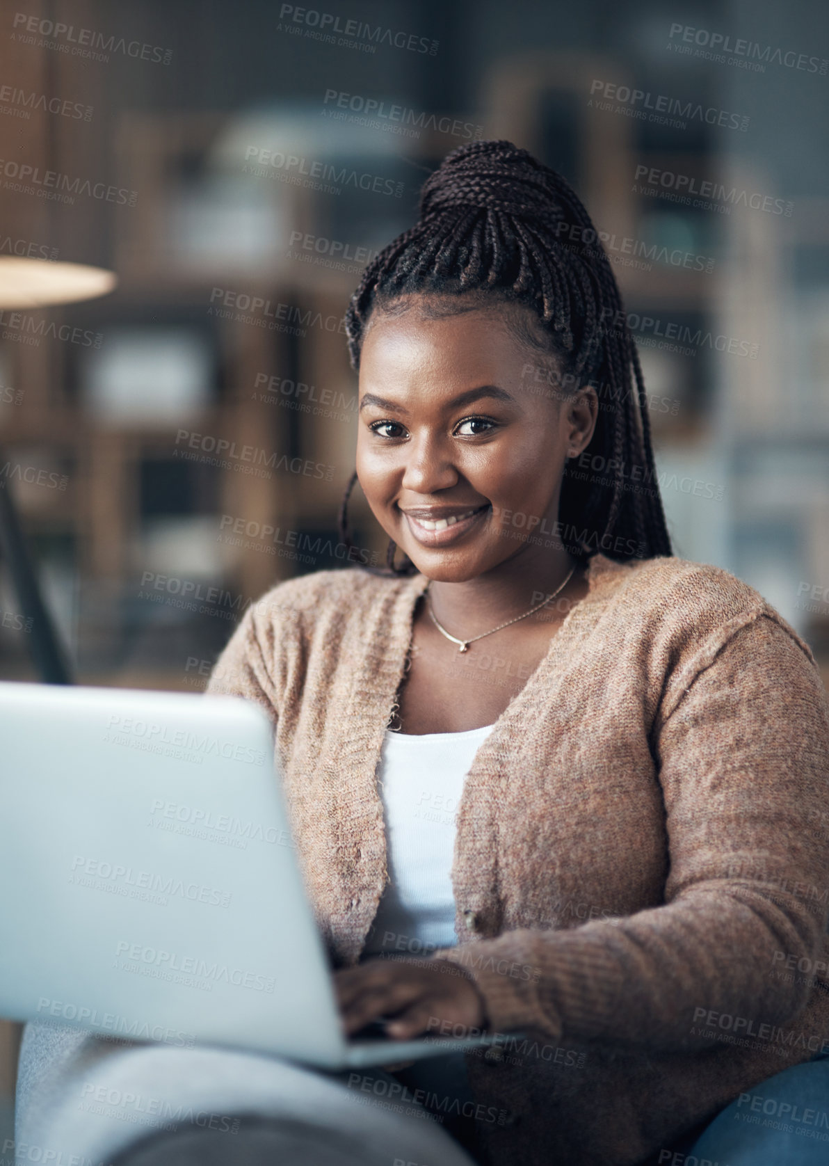 Buy stock photo Cropped shot of an attractive young woman sitting alone in her living room and using her laptop