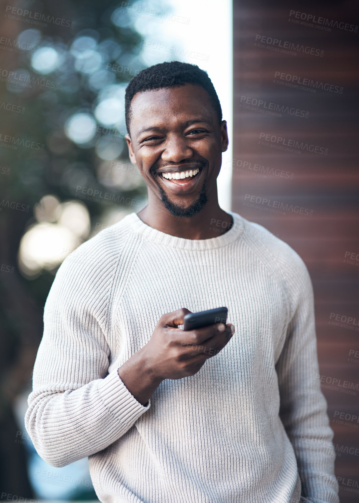 Buy stock photo Cropped shot of a handsome young man standing outside alone and using his cellphone